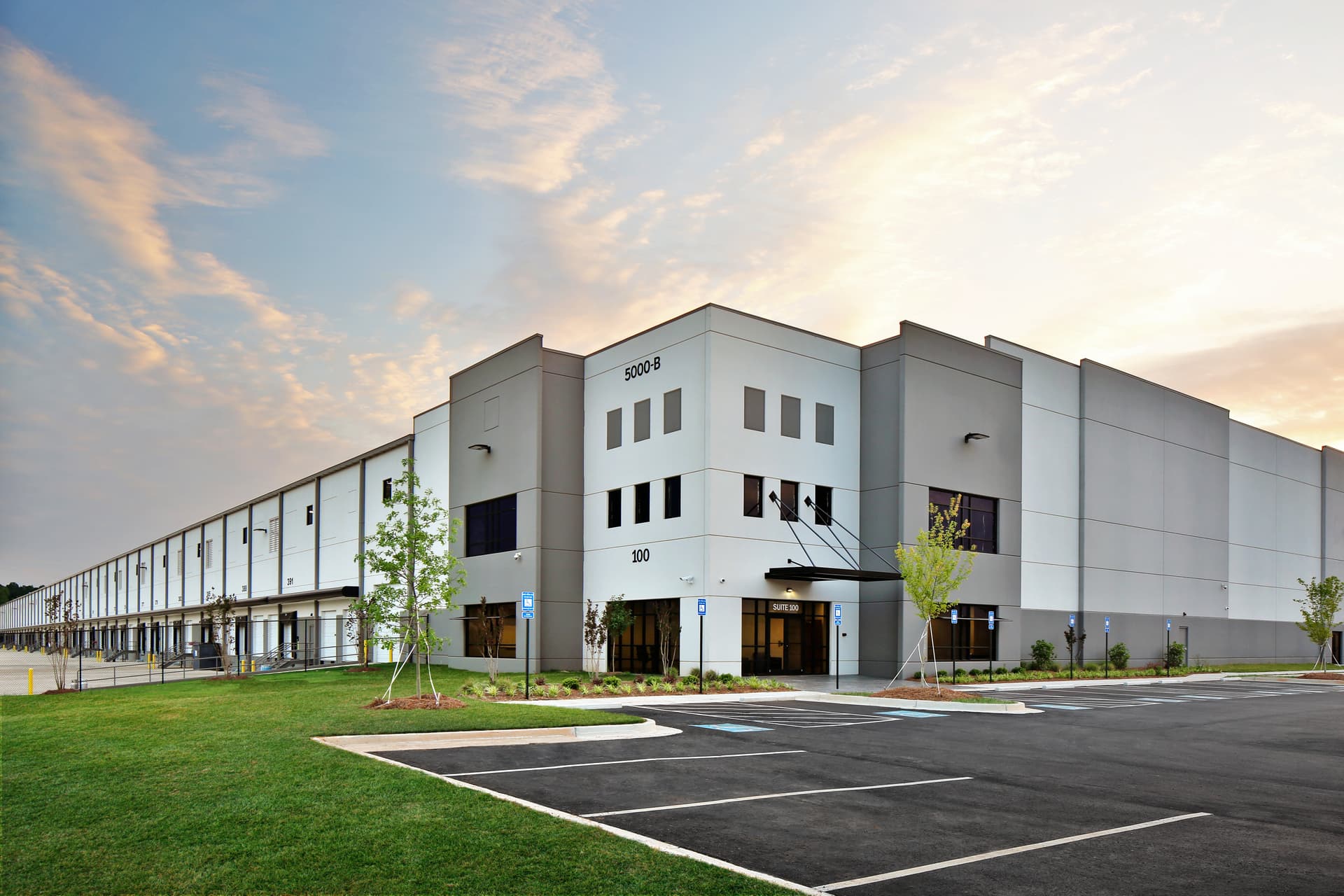 Modern gray warehouse distribution facility at sunrise